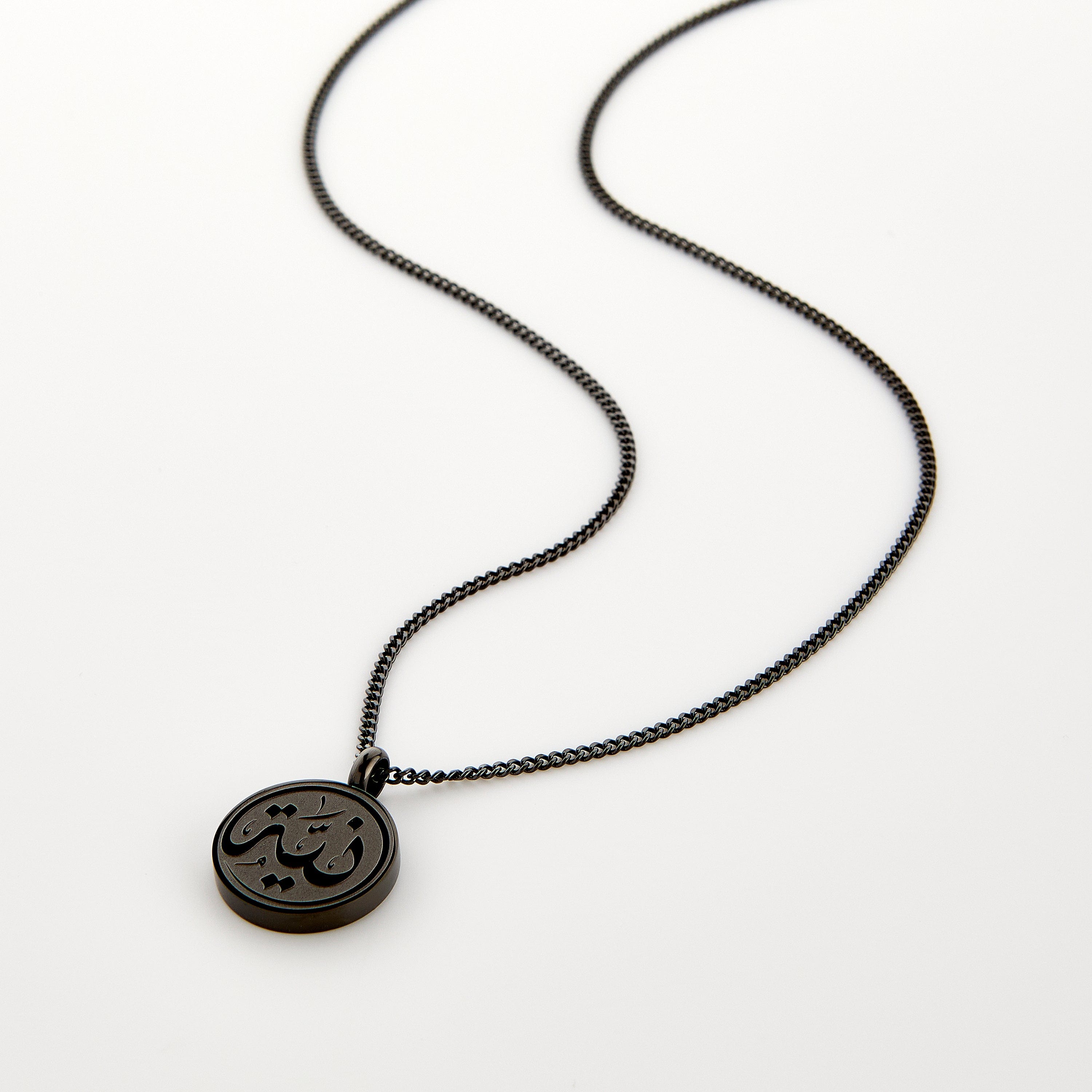 Black necklace with a circular pendant engraved with 'Niyyah' calligraphy, displayed on a white background.