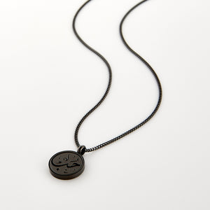 Black necklace with a circular pendant engraved with 'Hub' calligraphy, displayed on a white background.