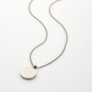 Silver necklace with a circular 'Sabr' calligraphy engraved pendant, displayed on a white background.