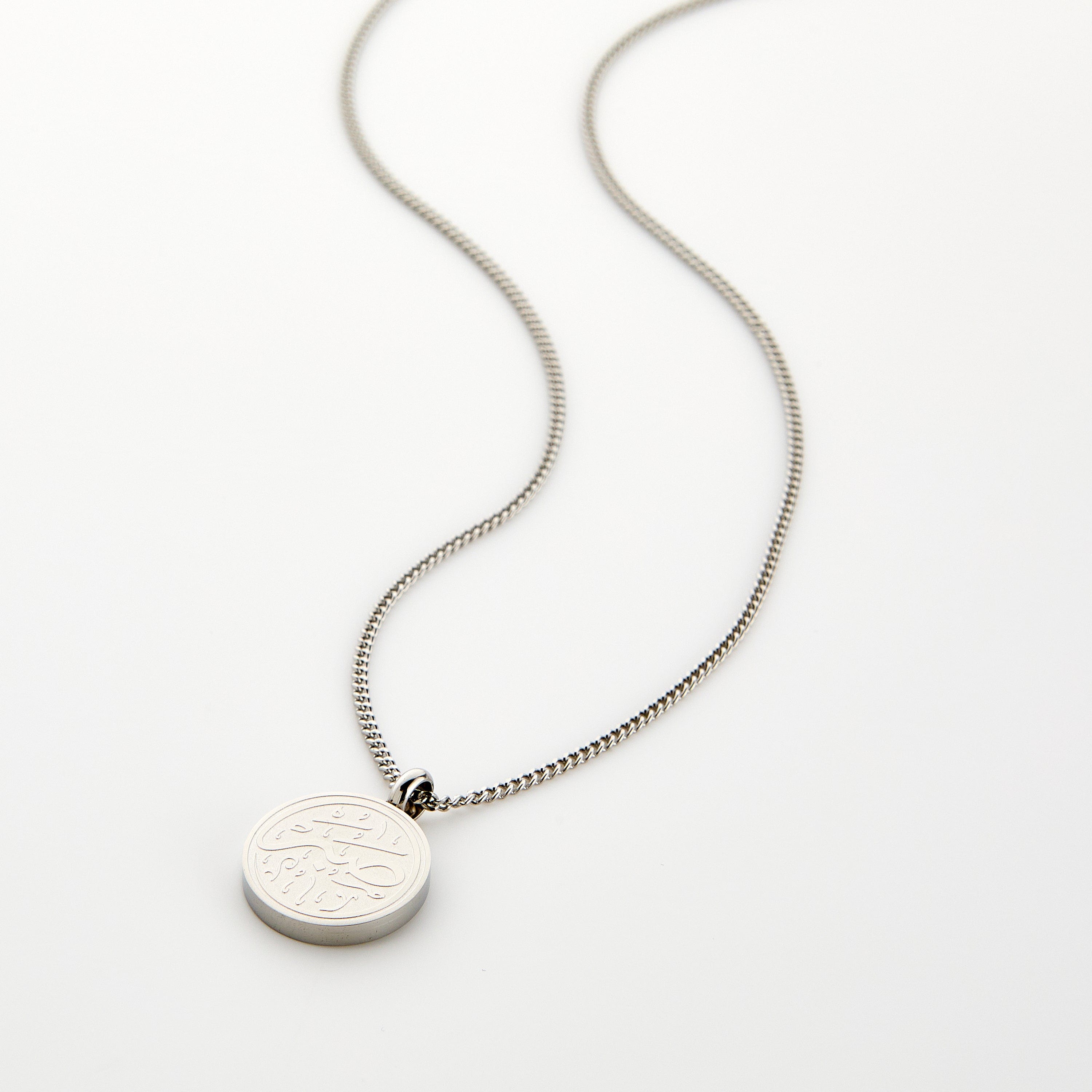 Silver necklace with a circular 'Sabr' calligraphy engraved pendant, displayed on a white background.