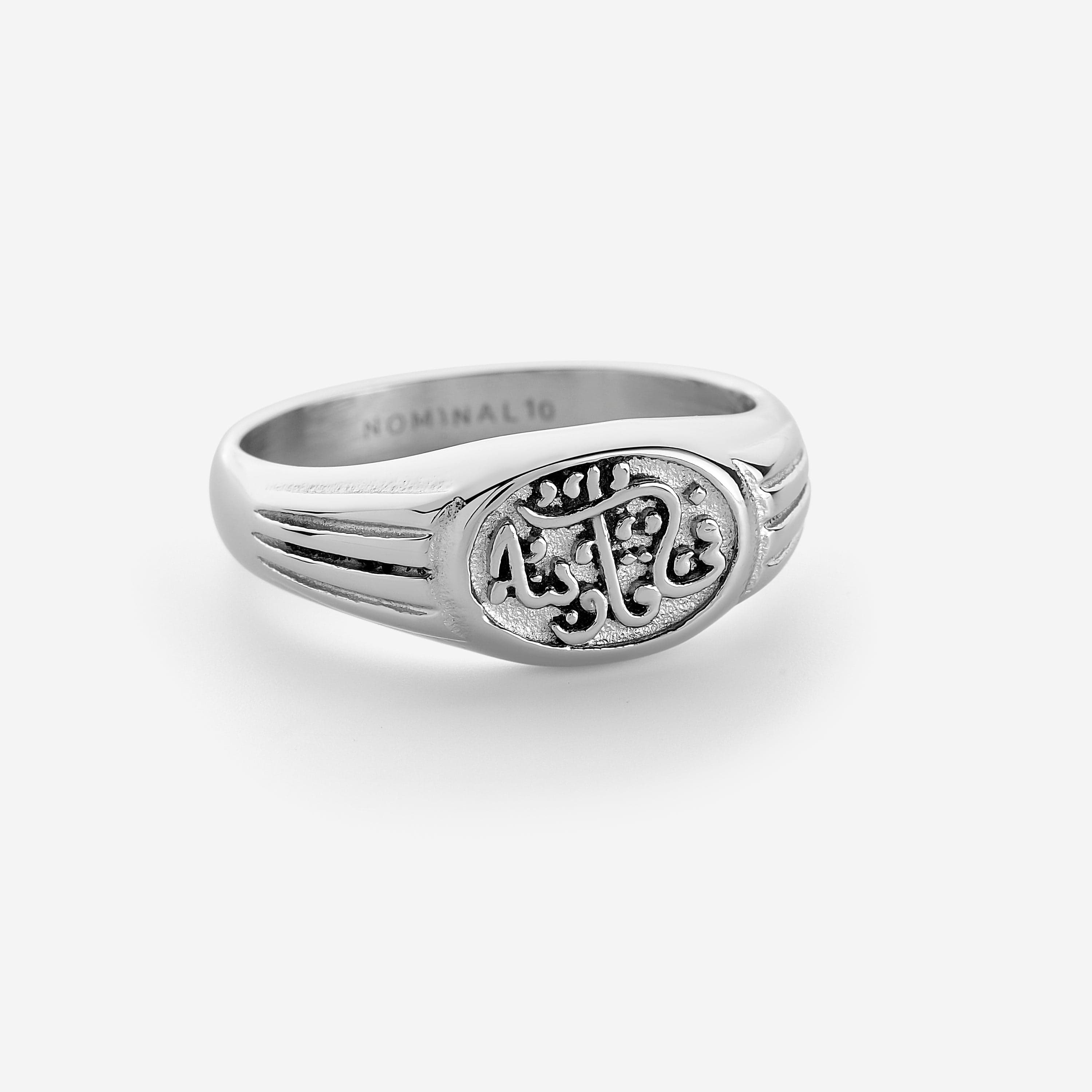 Photo of a silver ring featuring embossed lines around the band that lead to a plate that says "in our hearts"
