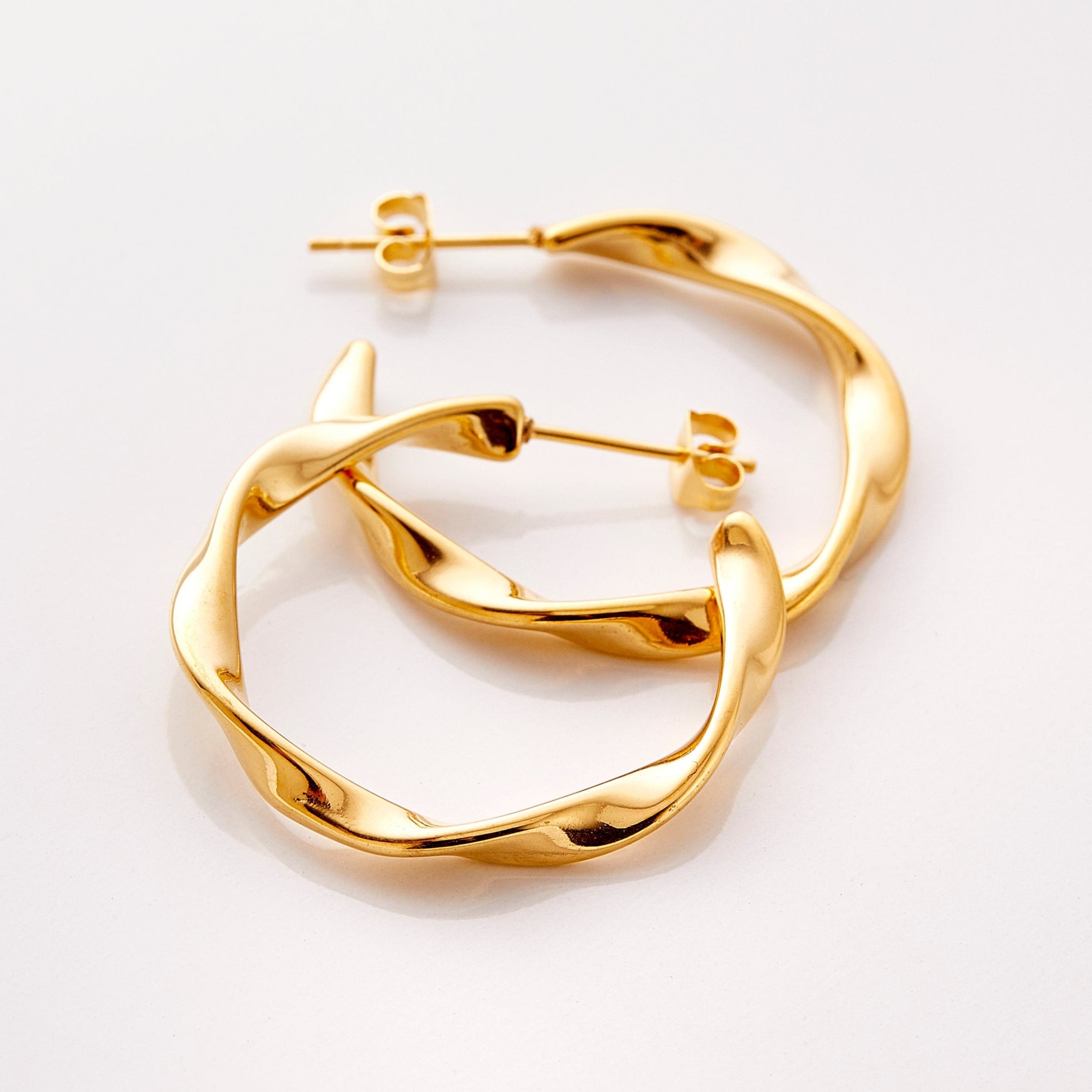 The gold Ripple Hoop Earrings against a white background.