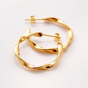 The gold Ripple Hoop Earrings against a white background.