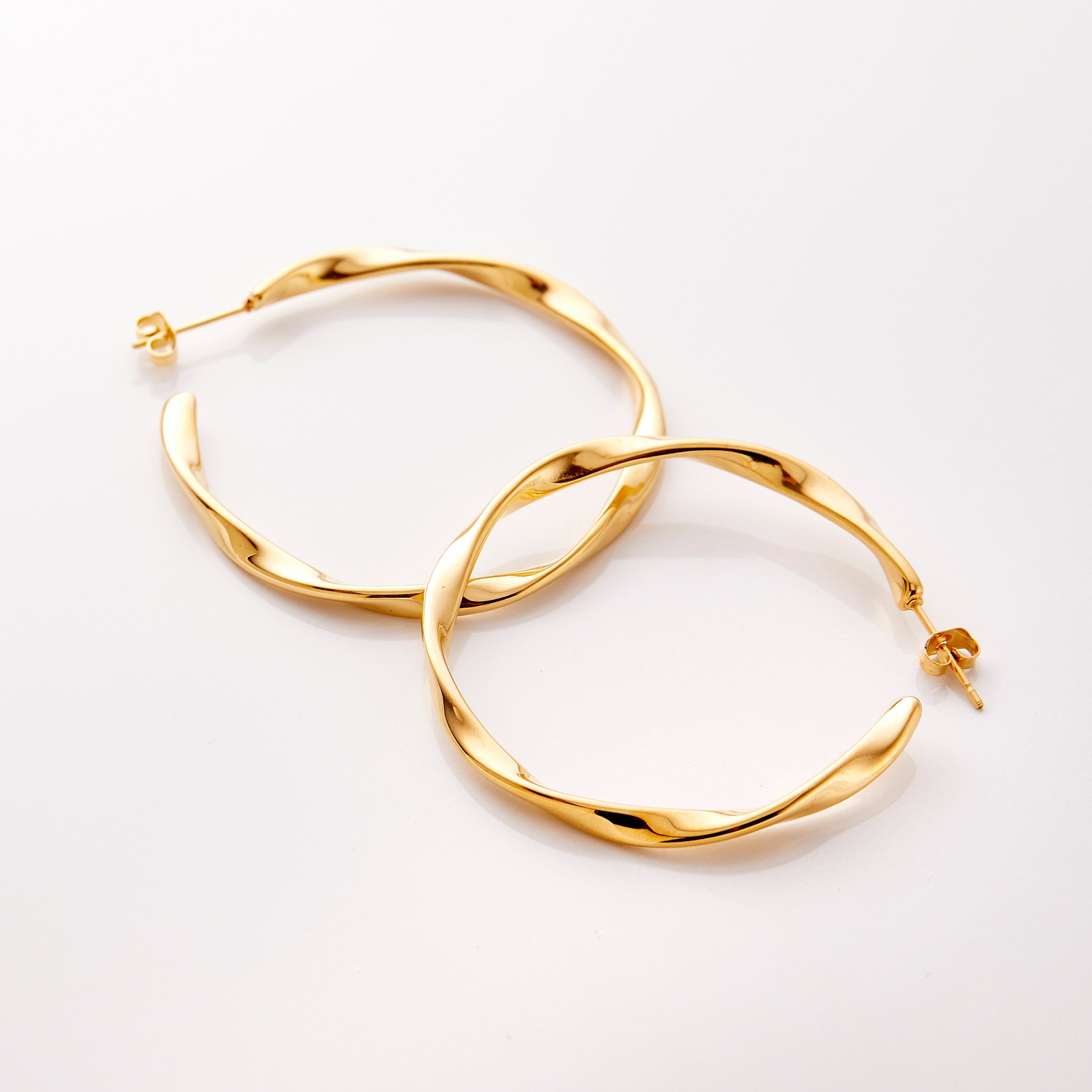 The gold Ripple Hoop Earrings against a white background.