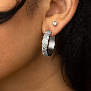 Close up photo of the model's left ear wearing the silver earrings and a simple circle stud earrings.