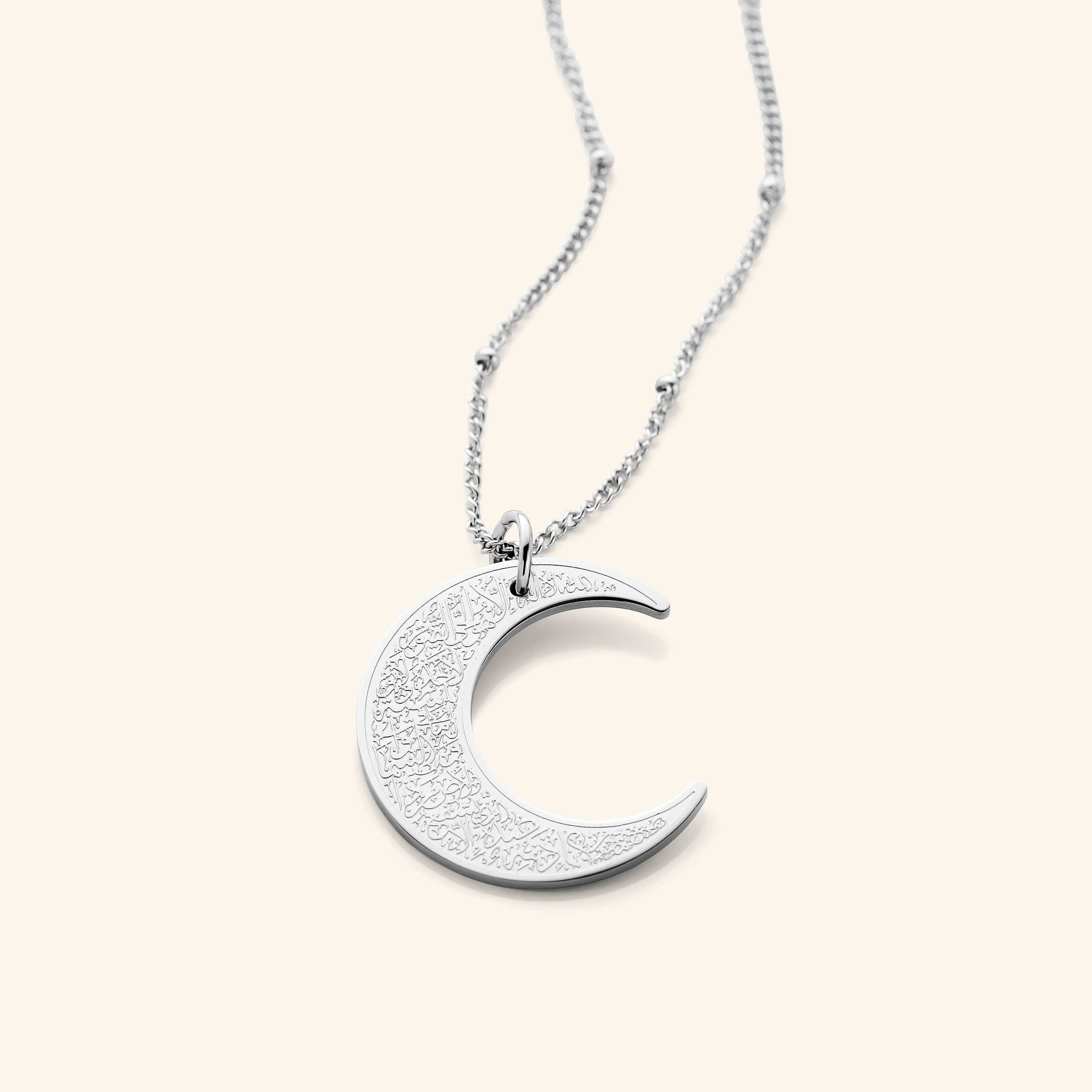The Ayatul Kursi Crescent Necklace in a polished silver finish, showcasing a crescent pendant adorned with detailed Arabic inscriptions, hanging from a fine silver chain.