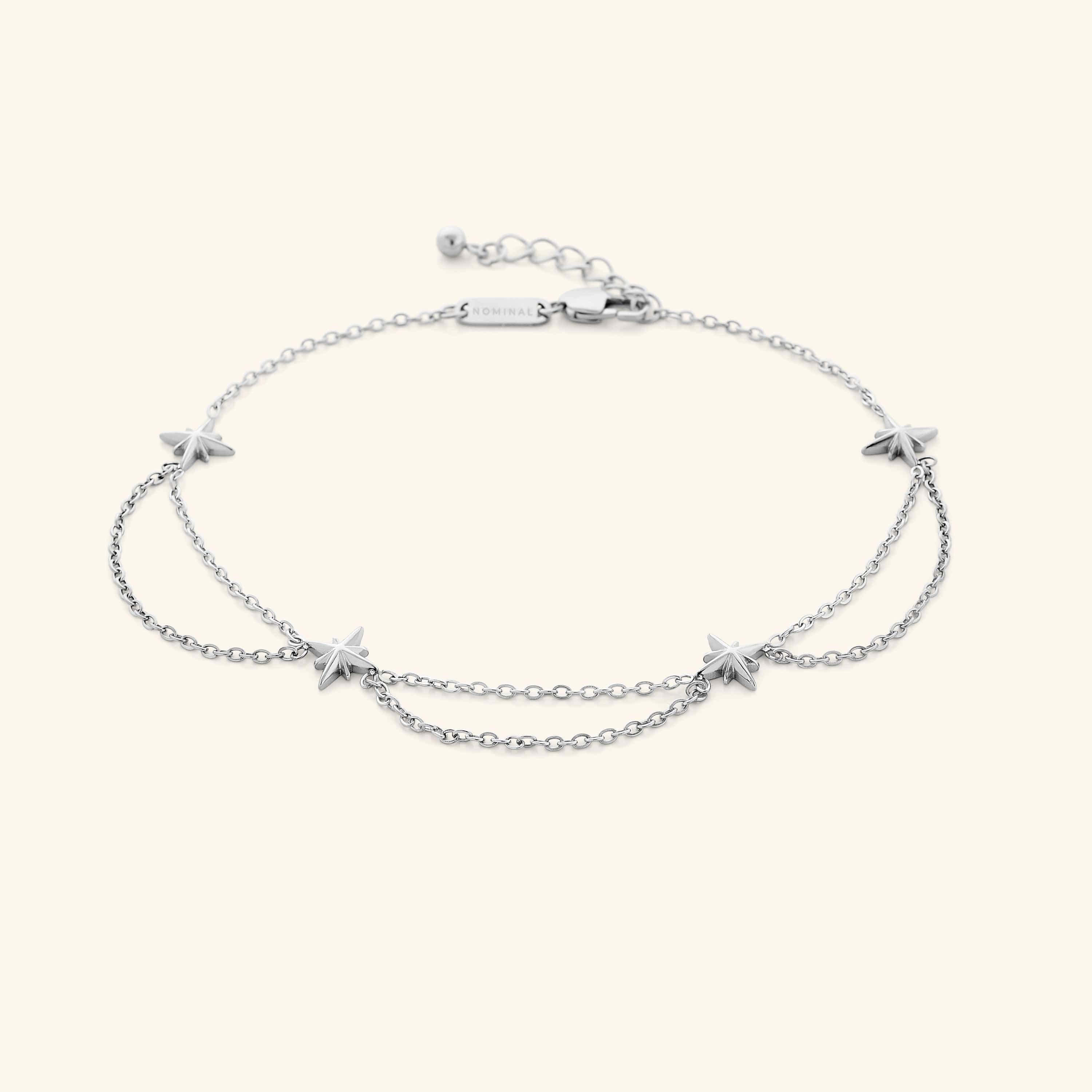 A silver anklet that features north stars all along the chain, drooping chains connecting each one design.