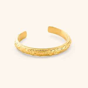 An 18K gold plated cuff etched with jasmine, marigolds, and water lilies art.