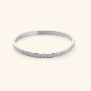 A slim silver bangle etched with geometric patterns pulled from Damascus tilework.