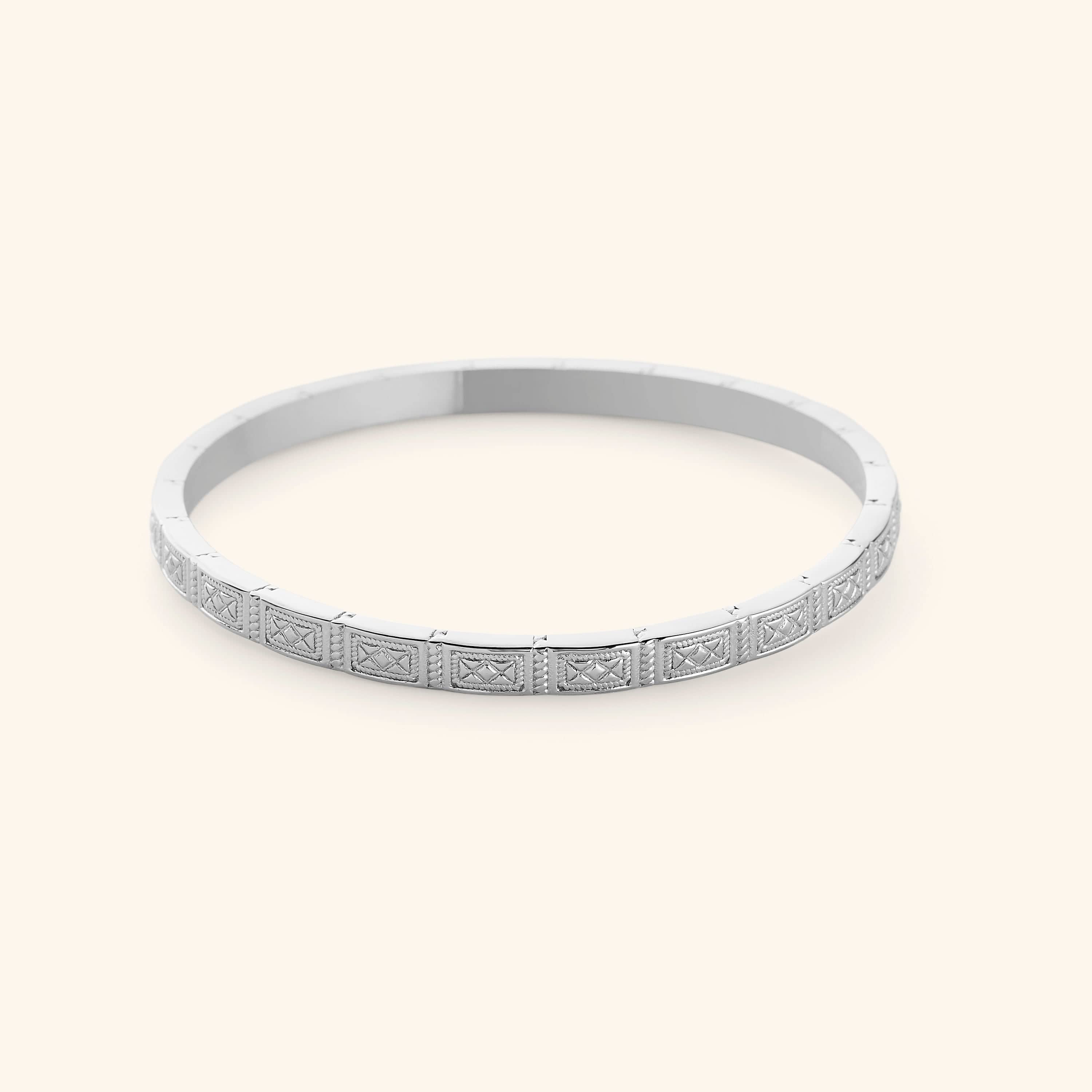 A slim silver bangle etched with geometric patterns pulled from Damascus tilework.