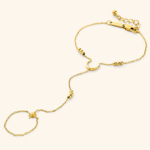 Gold lunar handchain featuring a delicate chain design with a crescent moon centerpiece, bead accents, and a small star charm connected to a finger loop, displayed on a neutral background.