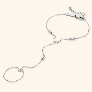 Silver lunar handchain featuring a delicate chain design with a crescent moon centerpiece, bead accents, and a small star charm connected to a finger loop, displayed on a neutral background.