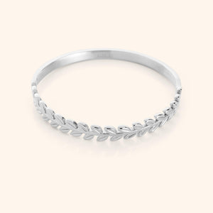 The Palestine Olive Layering Bangle in a polished silver finish, showcasing a twisted olive branch motif on one half and a smooth, minimalist band on the other, combining traditional symbolism with contemporary design.