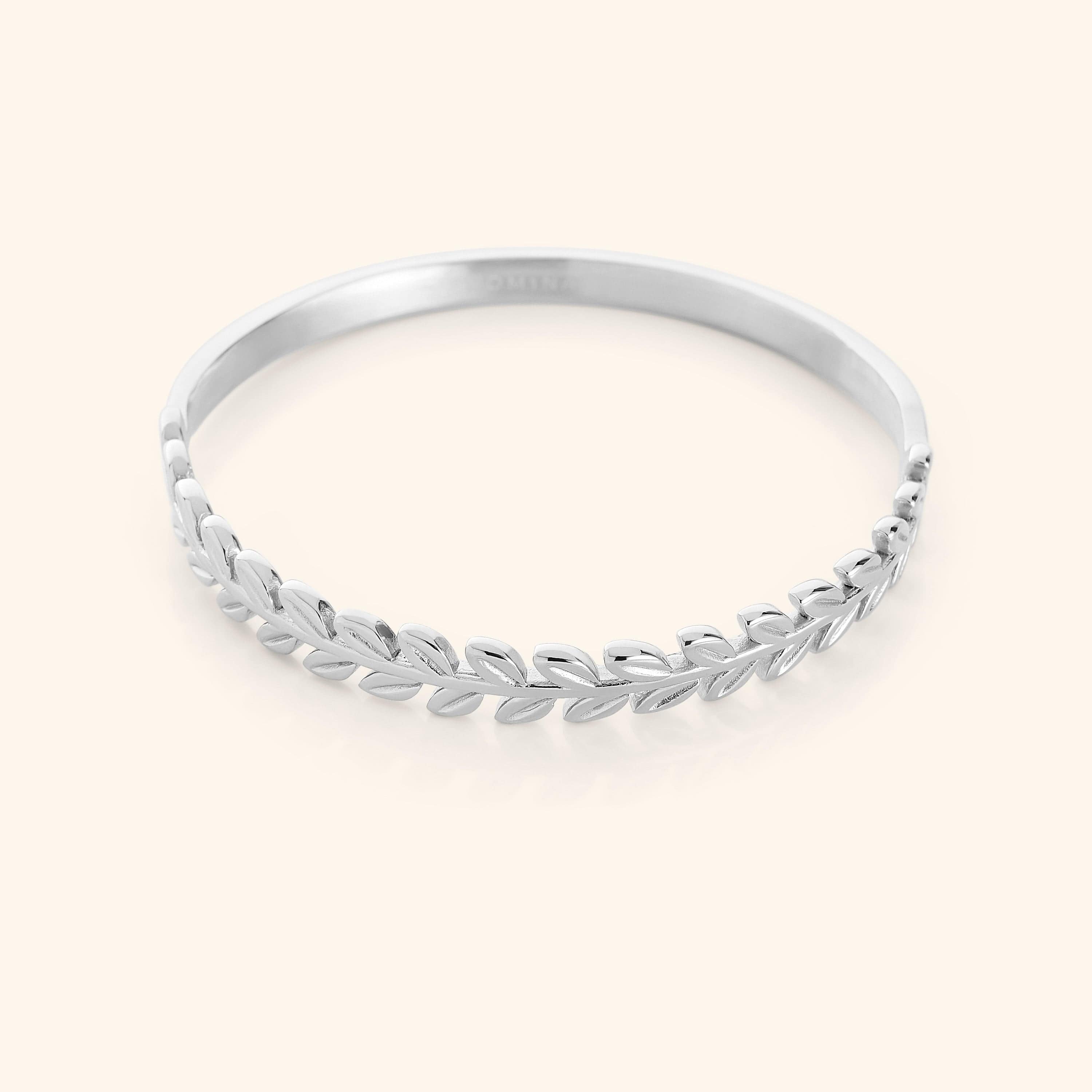 The Palestine Olive Layering Bangle in a polished silver finish, showcasing a twisted olive branch motif on one half and a smooth, minimalist band on the other, combining traditional symbolism with contemporary design.