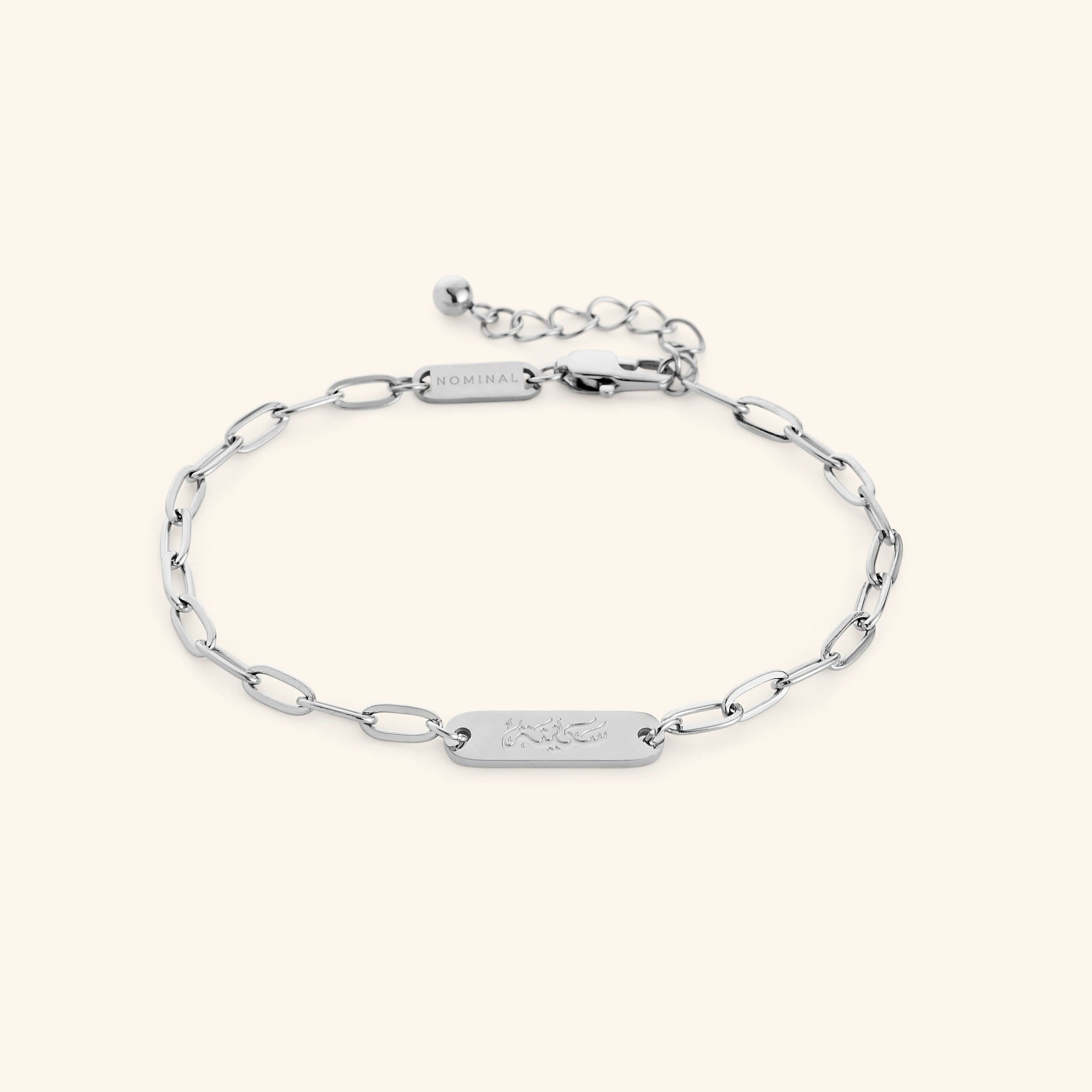 Silver Sakinah Serenity link bracelet showing the Arabic engraving on center tag, photographed against a light background.