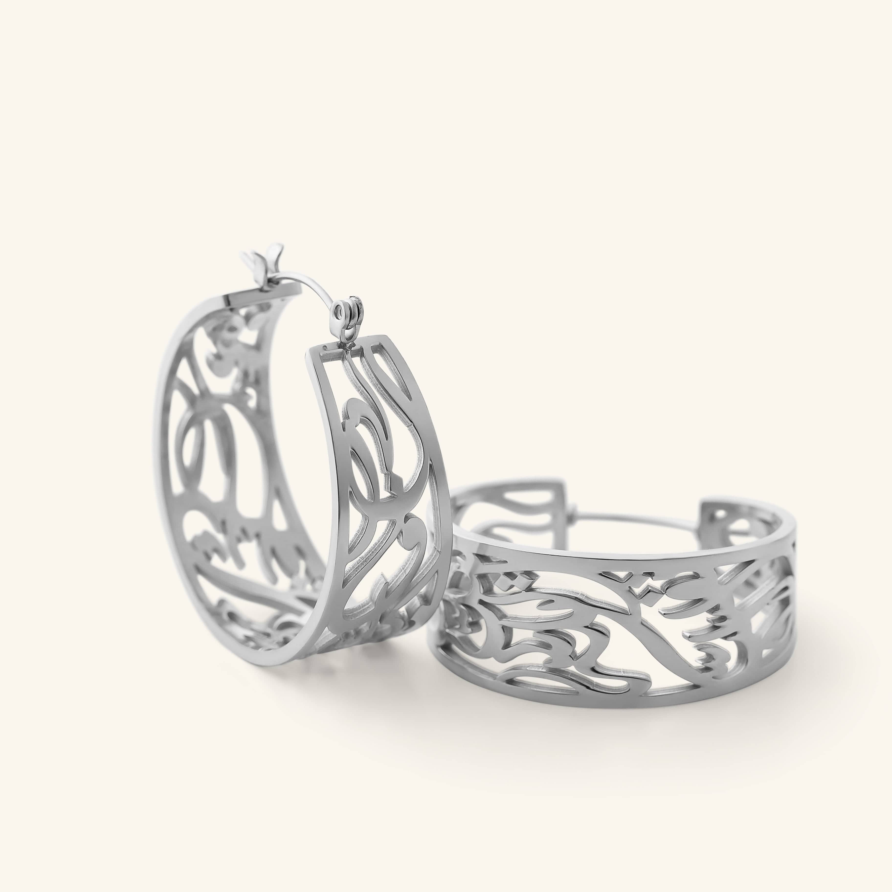 Close-up of the silver “Allah does not burden a soul beyond what it can bear” Earrings, showing the open-cut Arabic calligraphy hoop design.