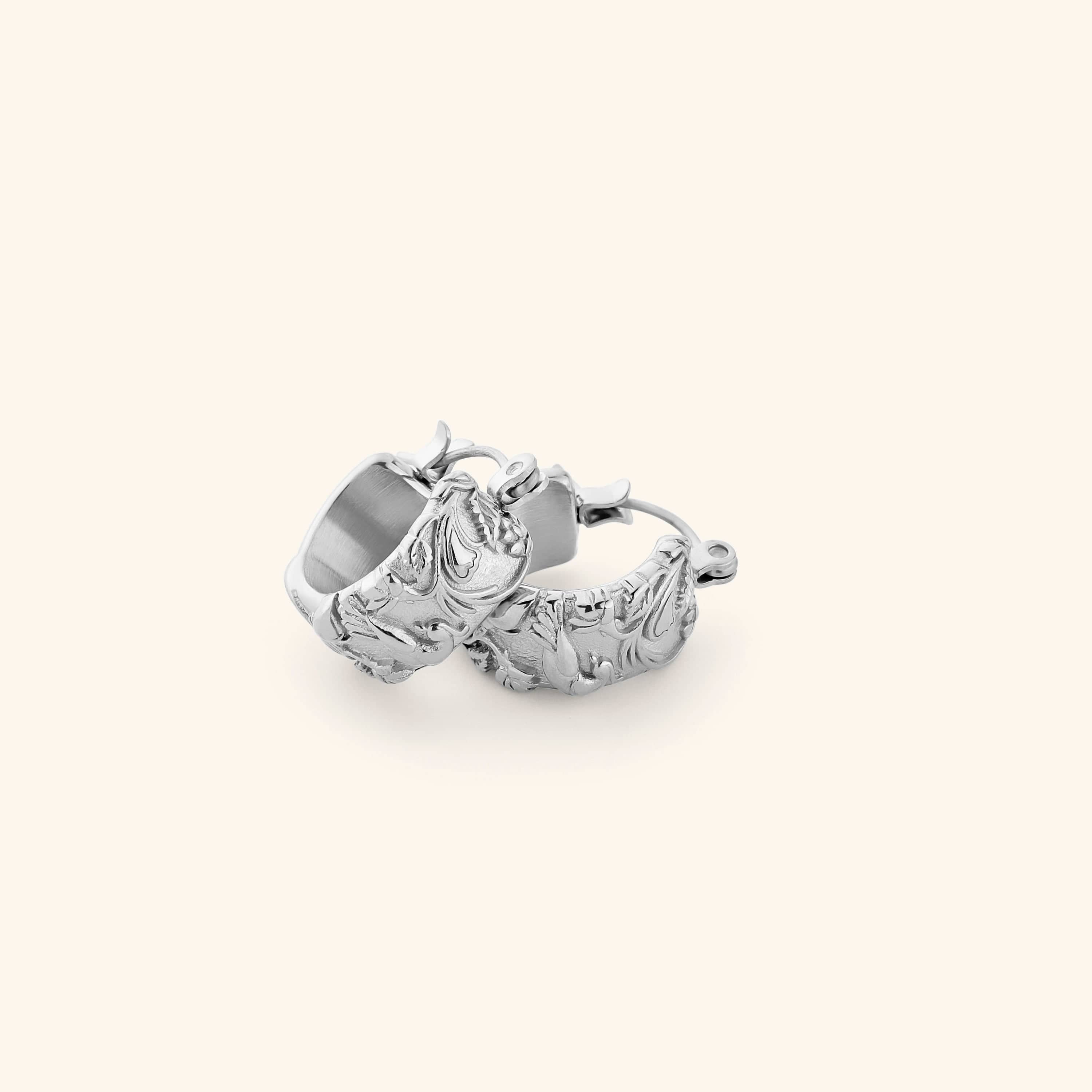 A pair of silver thick hoop earrings wrapped in jasmine, marigolds, and water lilies across the entire surface