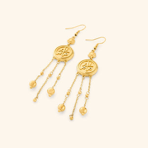 A pair of 18k gold plated coin earrings stamped with ماما (Mama) in Arabic, a miniature flower at the top, and each one trailing three delicate chains with spheres