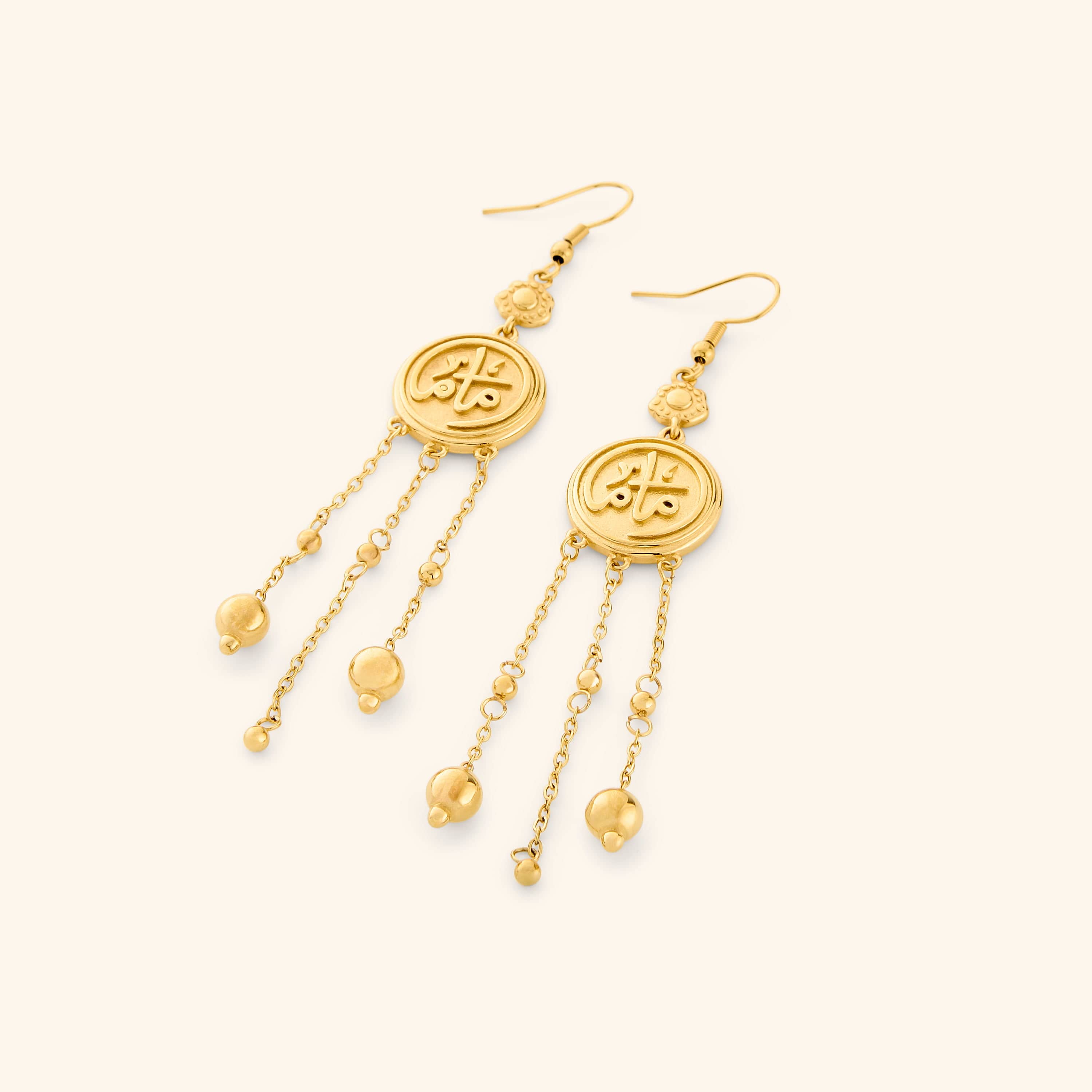 A pair of 18k gold plated coin earrings stamped with ماما (Mama) in Arabic, a miniature flower at the top, and each one trailing three delicate chains with spheres