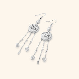 A pair of silver coin earrings stamped with ماما (Mama) in Arabic, a miniature flower at the top, and each one trailing three delicate chains with spheres