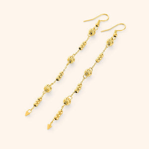 Flat lay of the 18k gold plated earrings. Comet Earrings drop 3.5 inches with delicate, evenly spaced orbs.