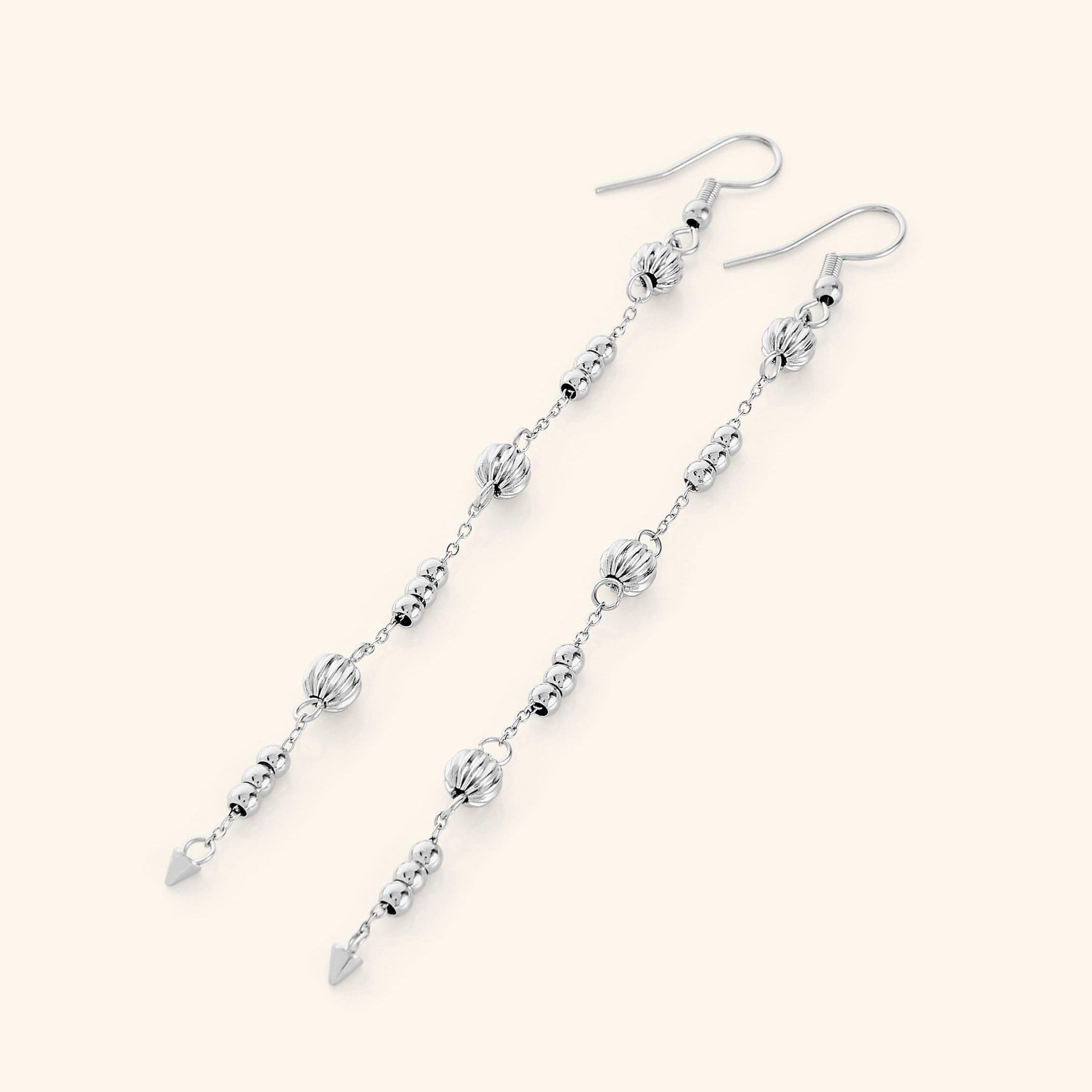 Flat lay of the silver earrings. Comet Earrings drop 3.5 inches with delicate, evenly spaced orbs.