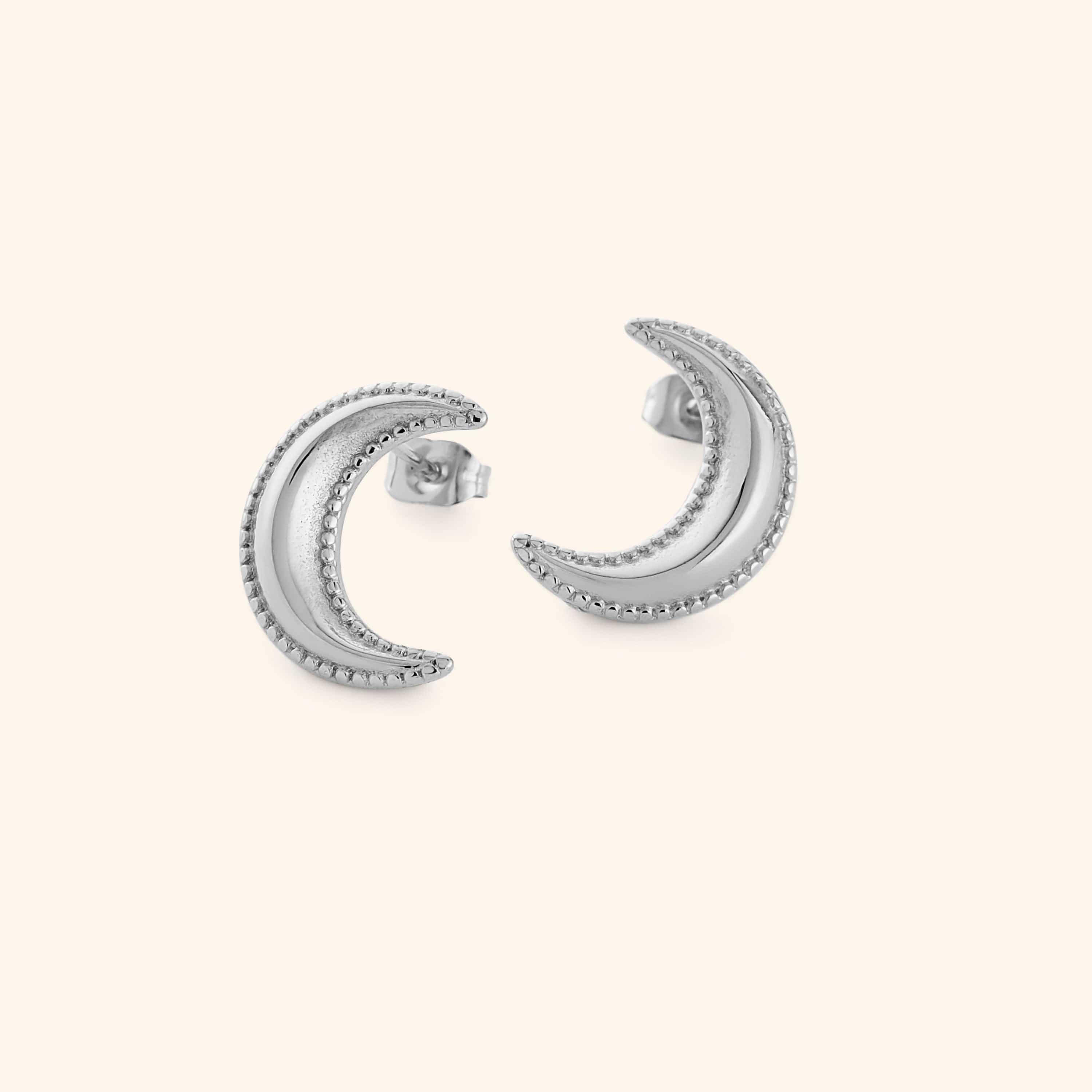 Silver crescent moon earrings with dotted design, shot on a white background