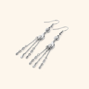  A pair of silver earrings that feature paisley droplets suspended from textured coins, each one trailing three delicate chains that move when you do.