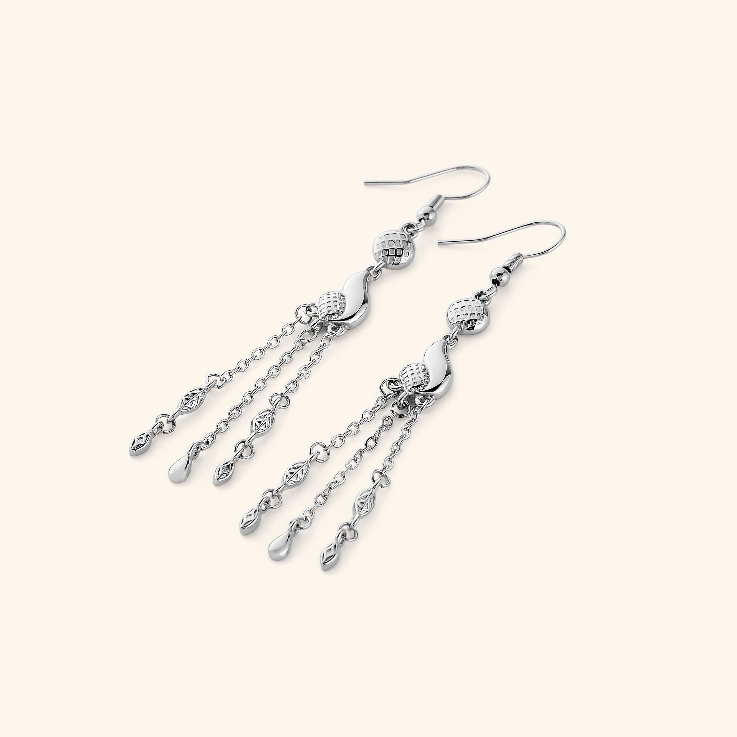  A pair of silver earrings that feature paisley droplets suspended from textured coins, each one trailing three delicate chains that move when you do.
