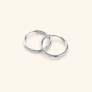 Flat lay of the silver Medium Essential Hoops | 16mm against a light background.