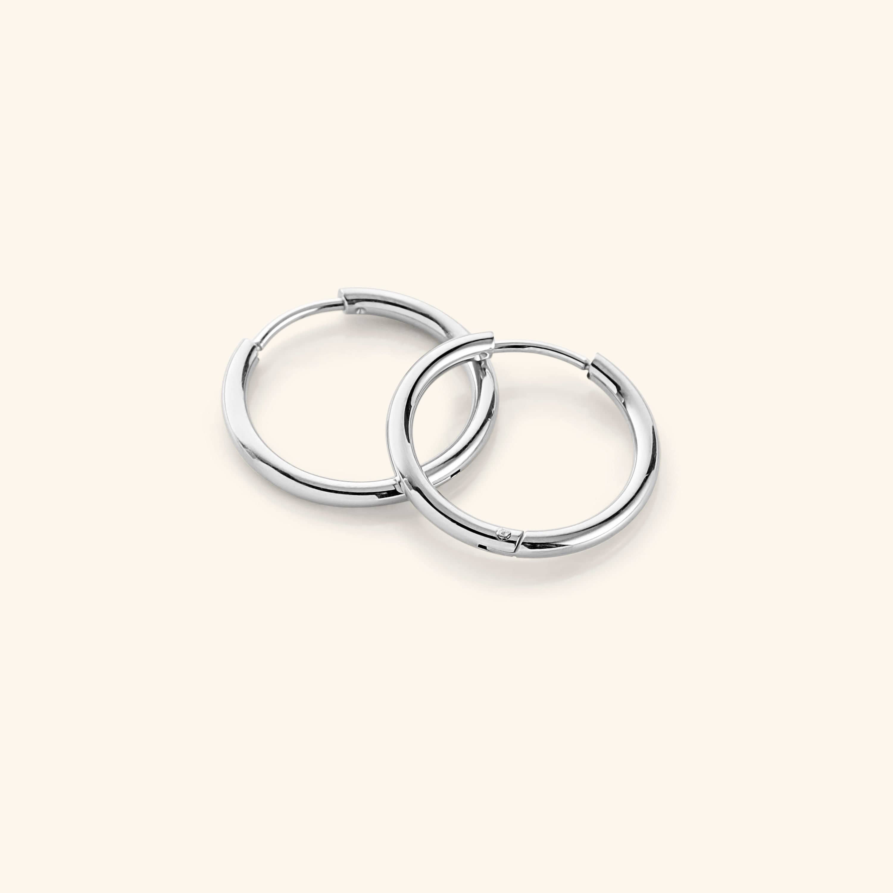 Flat lay of the silver Medium Essential Hoops | 16mm against a light background.