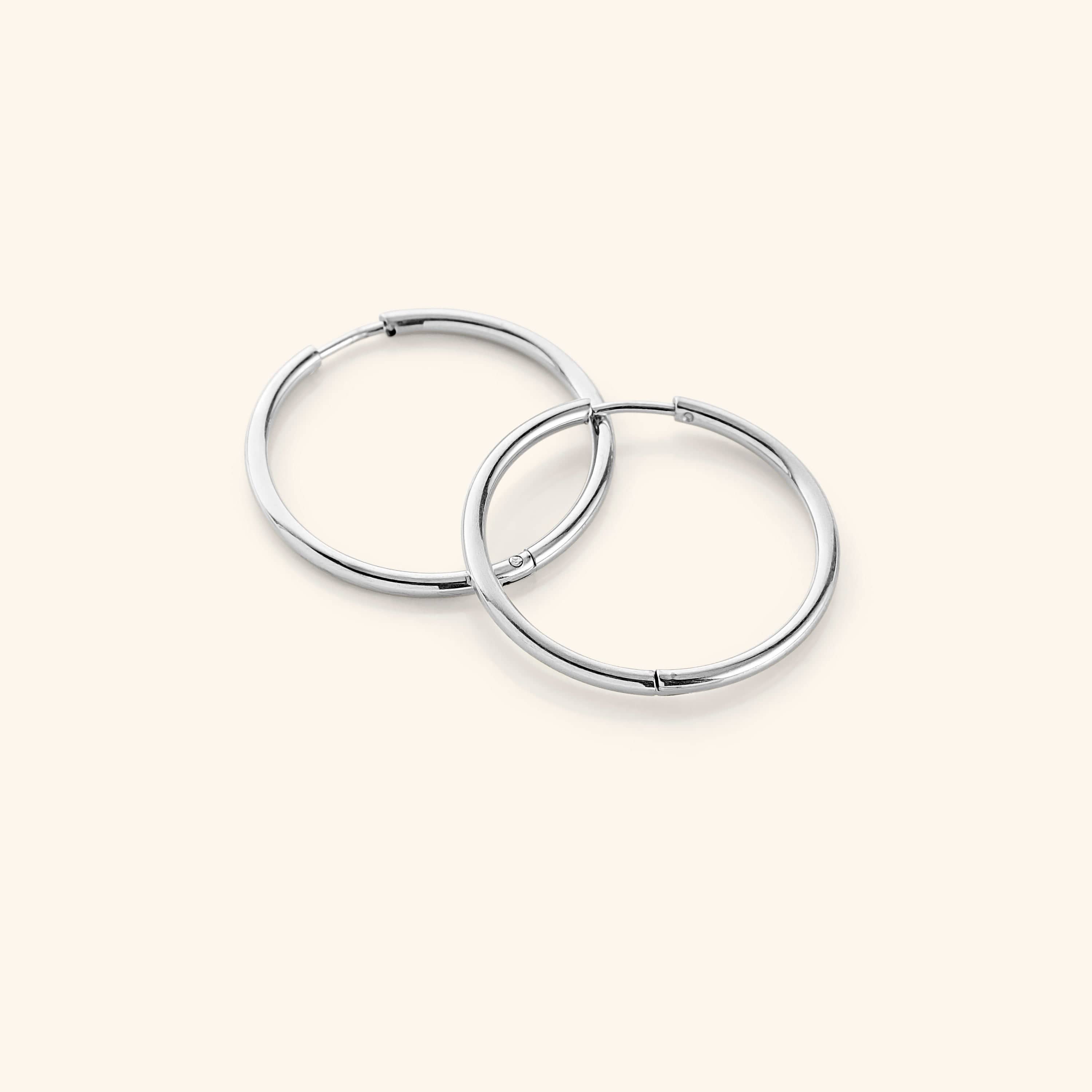 Flat lay of the silver Large Essential Hoops | 25mm against a white background.