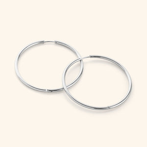 Flat lay of a pair of silver Oversized Essential Hoops | 40mm against a light background.