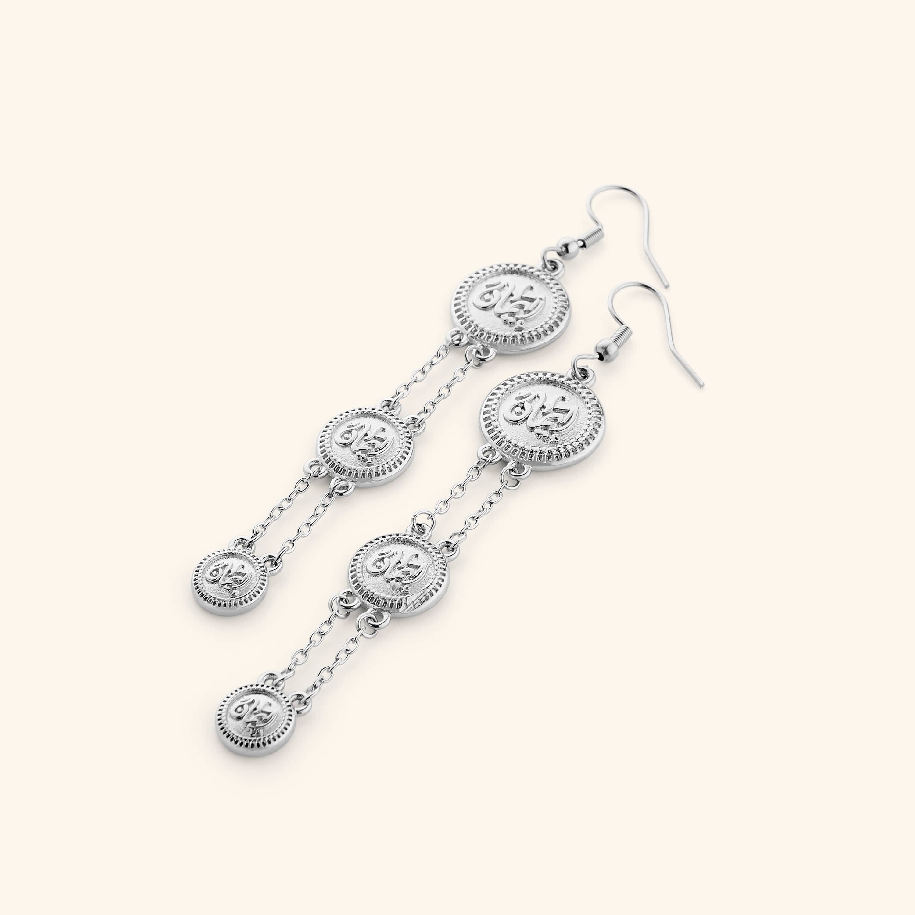 A pair of tri-coin silver earrings  embossed with Arabic calligraphy "Iman". The coins drape from each other with a silver double-chain.