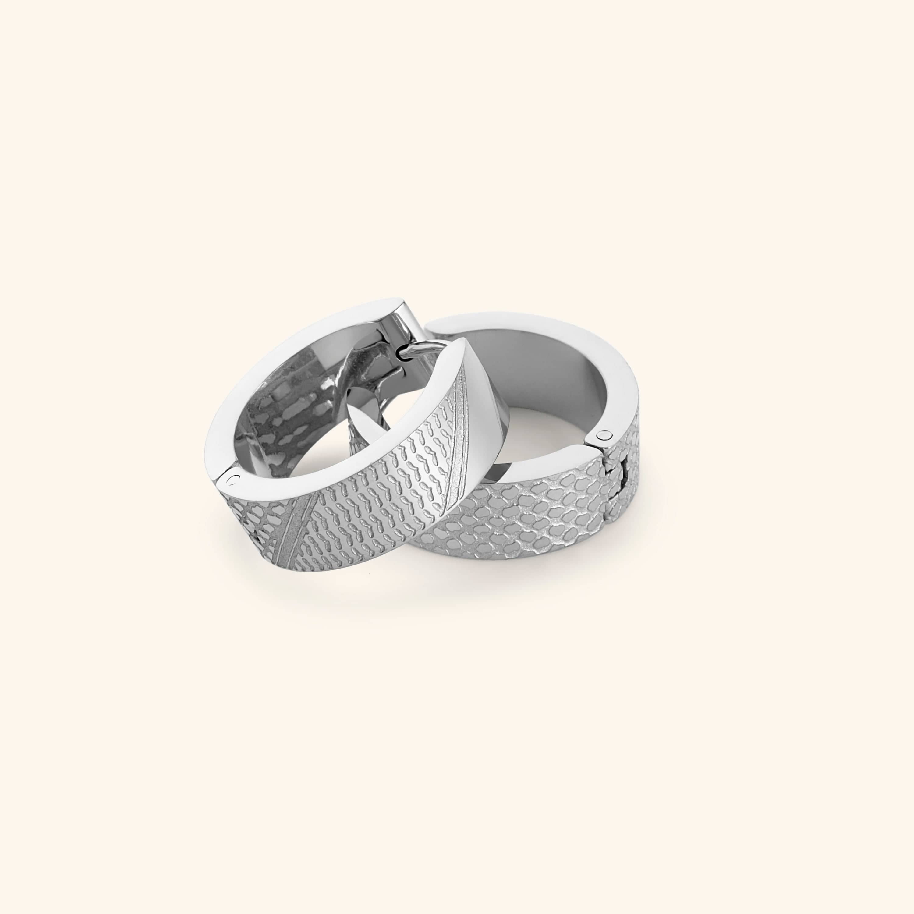 Pair of silver keffiyeh chunky hoops on a light background