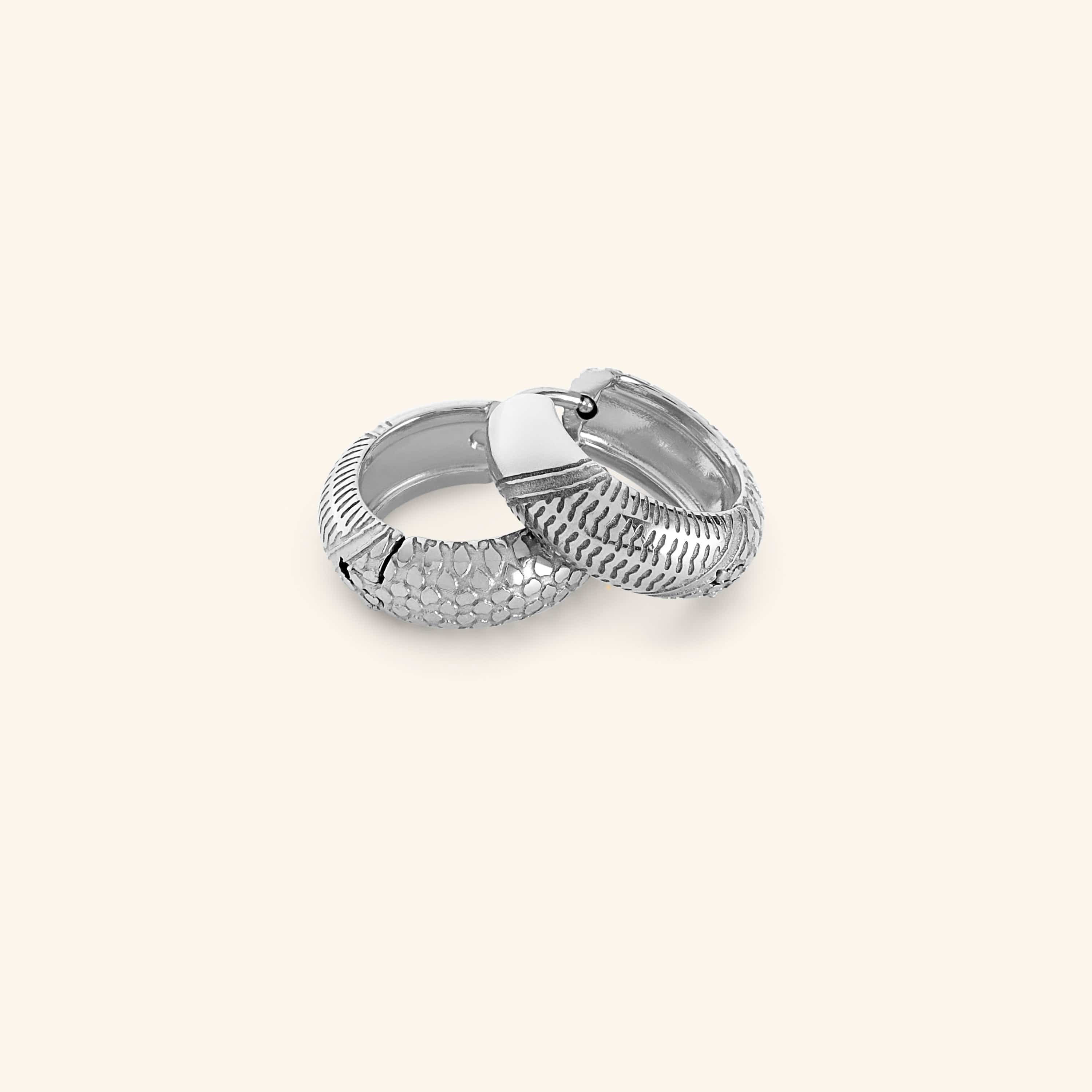 Pair of silver keffiyeh mini hoops on a light background