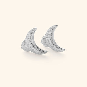 Silver earrings shaped in an upside down crescent featuring an Arabic quote inscribed on each saying "light comes after darkness."