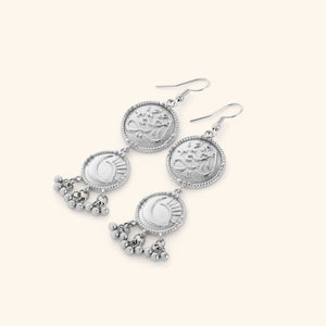 A pair of silver dangling earrings featuring the Arabic Calligraphy of "my sister" on the first coin, dropping into a moon and star on the second coin, finished with dancing orbs.