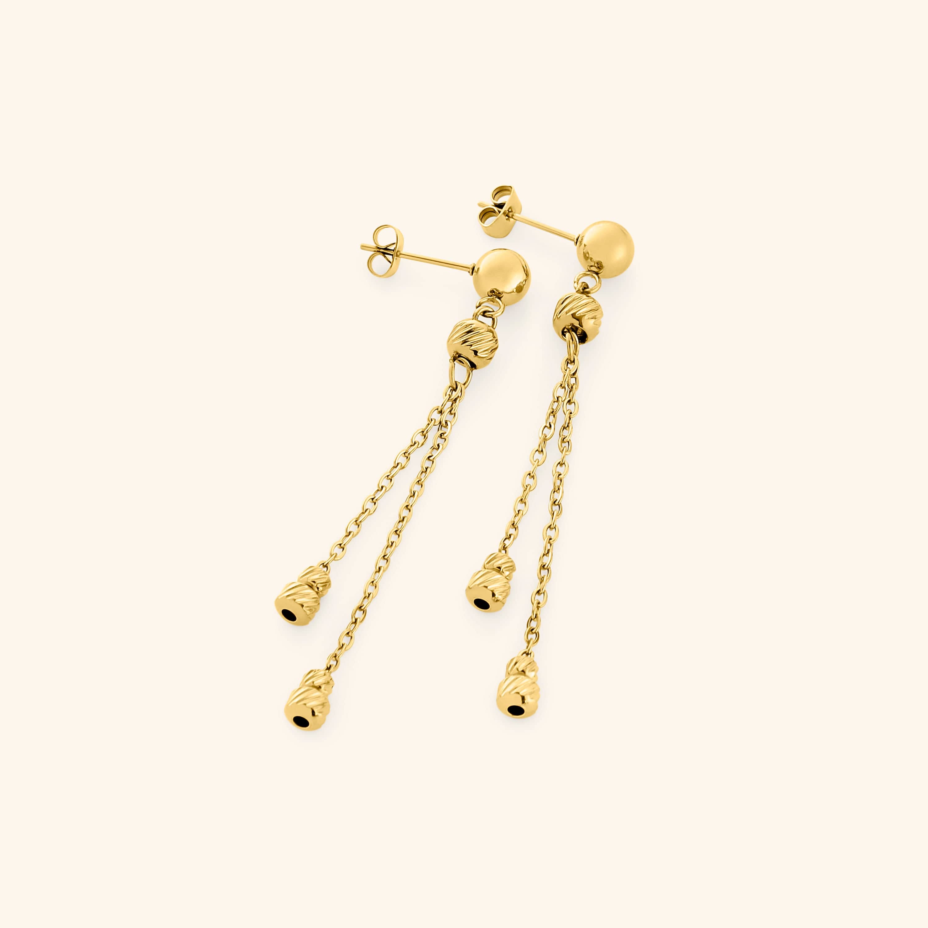 Pair of gold drop earrings featuring a polished stud with two slim chains, each ending in ribbed gold bead charms.
