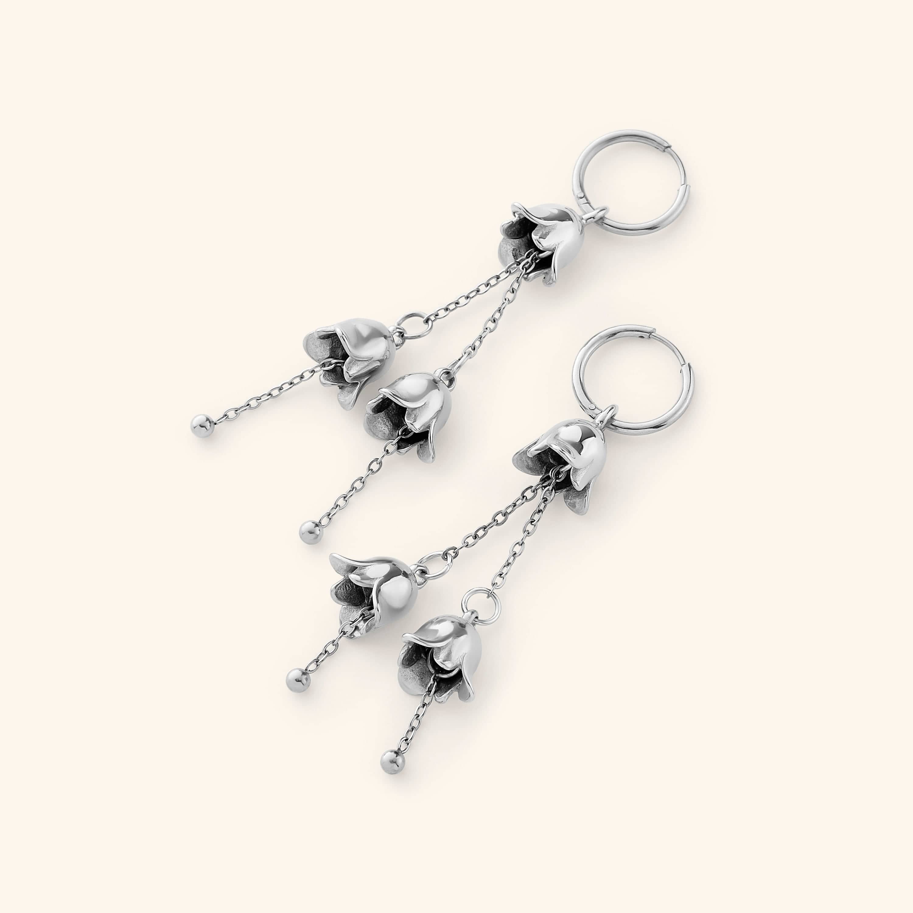 A pair of Raining Tulip Hoops in silver, showcasing the same floral-inspired dangling design on fine chains attached to hoops.