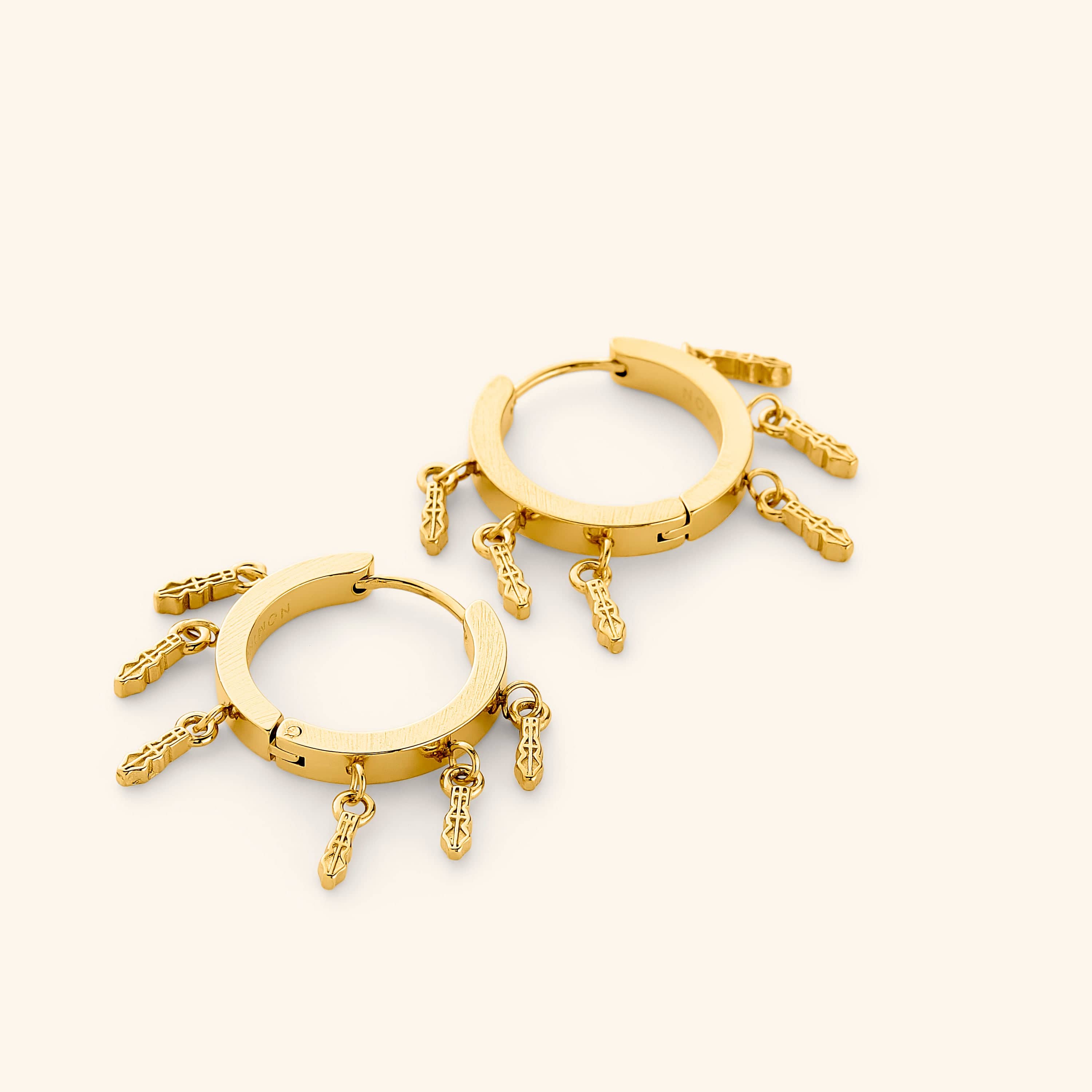 A pair of 18k gold plated chunky hoop earrings with tatreez patterns hanging beneath, each one carved with the traditional Palestinian embroidery