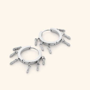 A pair of silver chunky hoop earrings with tatreez patterns hanging beneath, each one carved with the traditional Palestinian embroidery