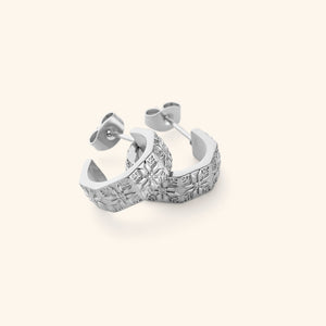 A pair of silver thick hoop earrings traced with tatreez.