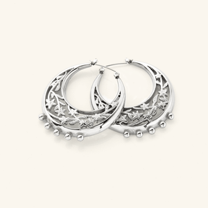 The Jasmine Crescent Hoop Earrings in a polished silver finish, showcasing a chunky hoop design adorned with an intricate jasmine vine that gracefully weaves through the crescent shape, blending celestial inspiration with botanical beauty