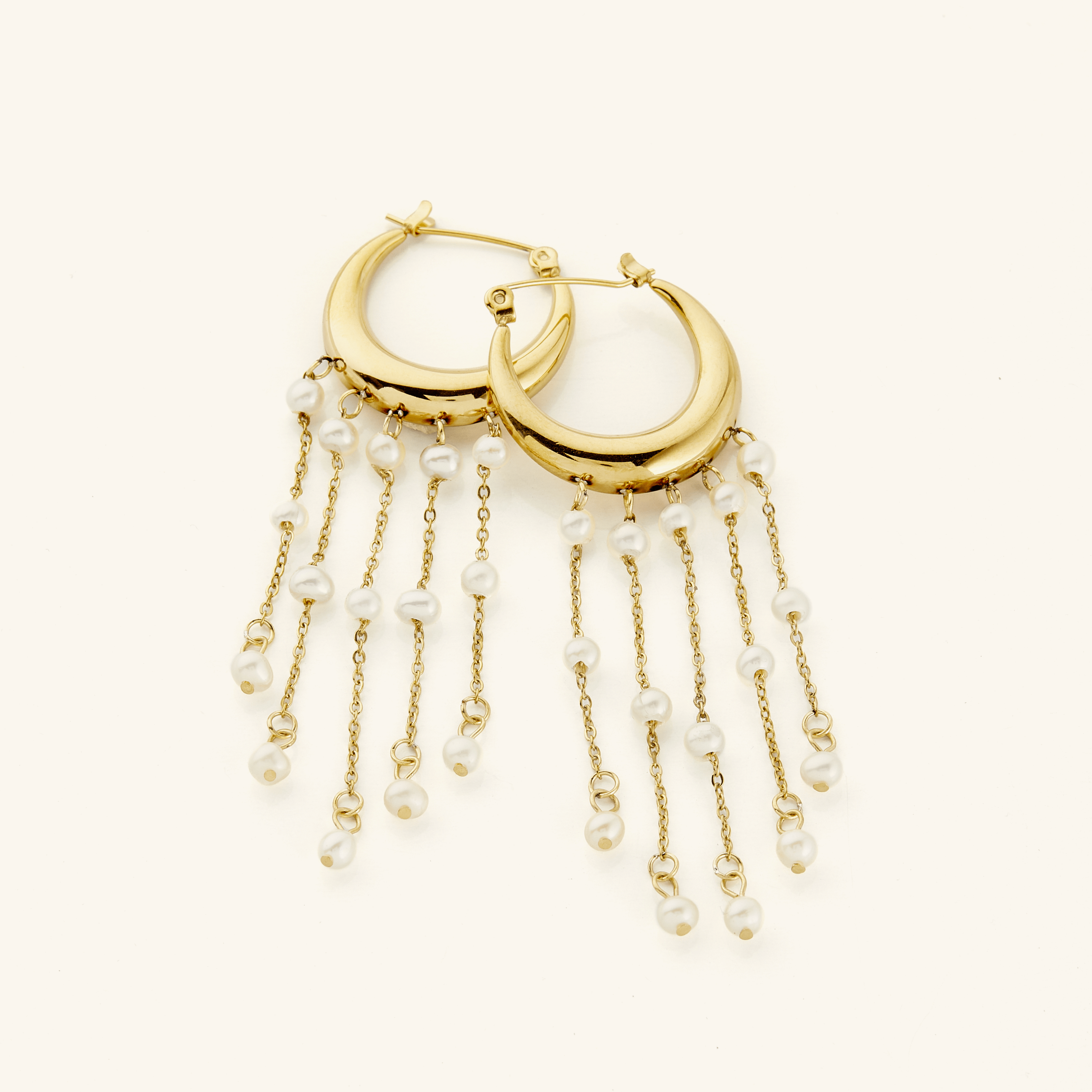 A pair of 18k gold plated earrings crafted in the shape of a delicate crescent, this hoop gracefully extends to embrace a cascade of raining pearls at its bottom.