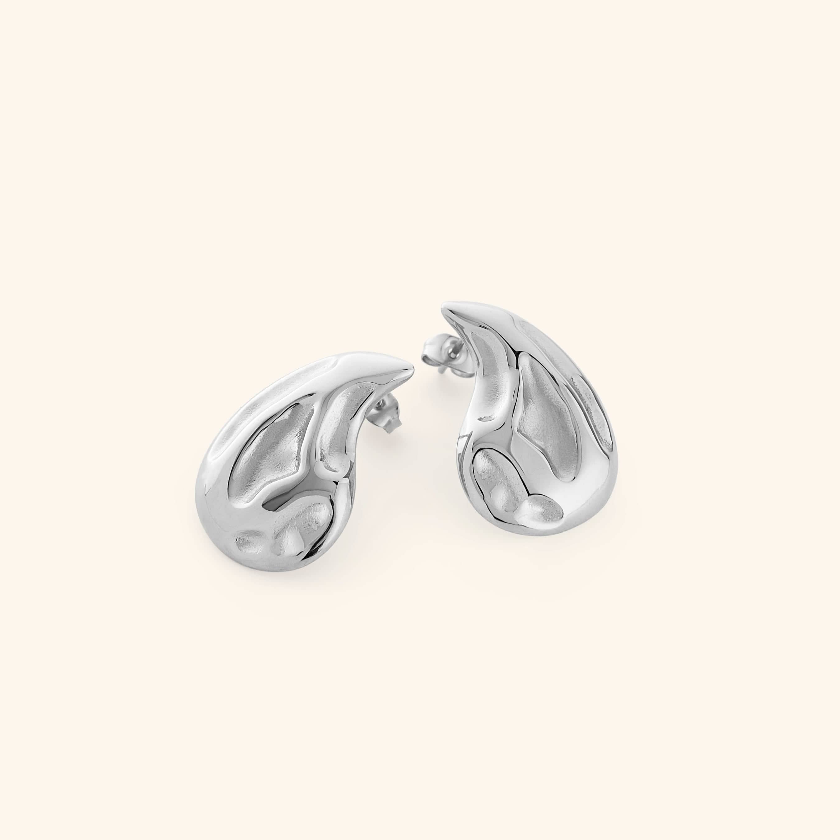 Pair of silver earrings shaped like a droplet, shot on a white background