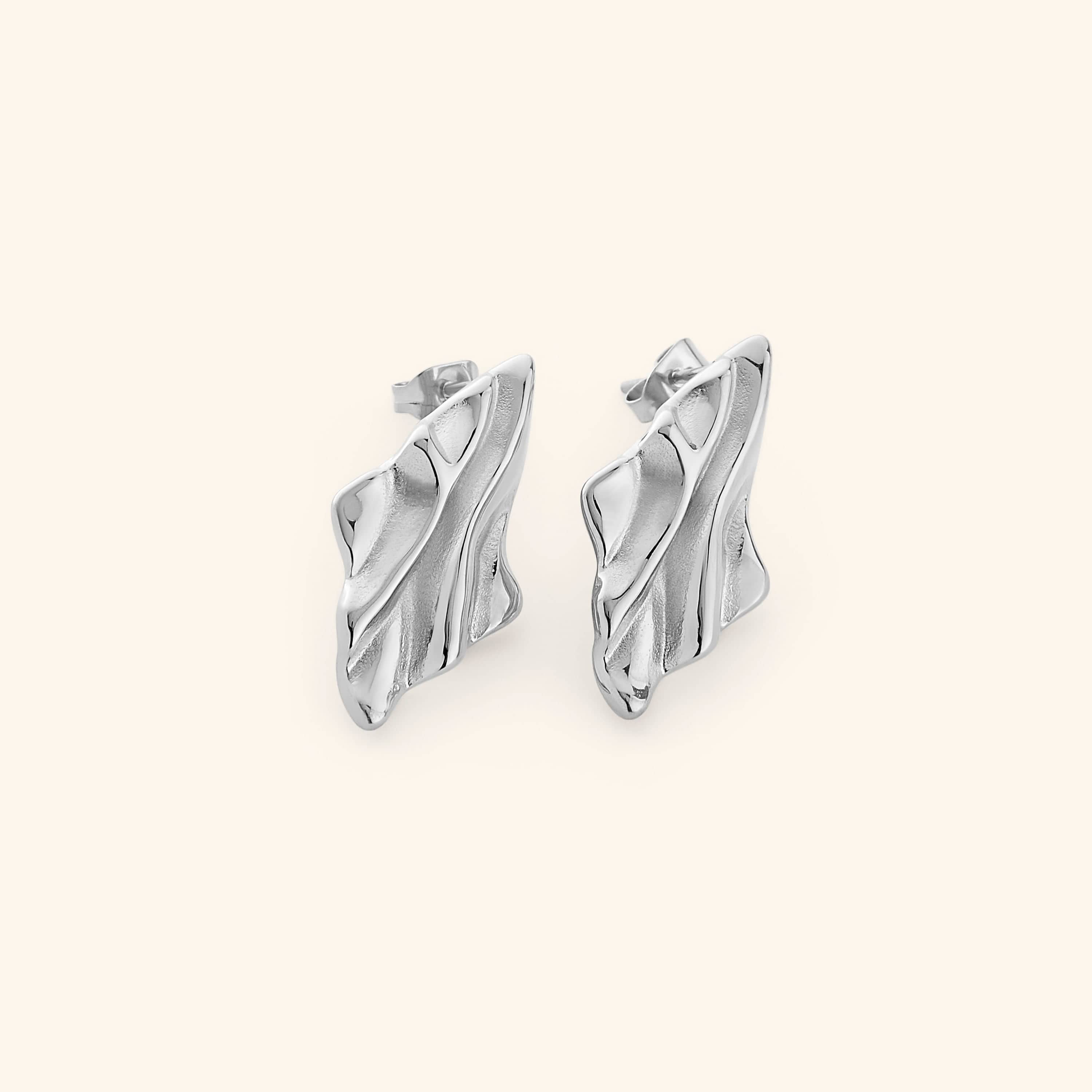 Pair of silver earrings with a melted design appearance, on a white background