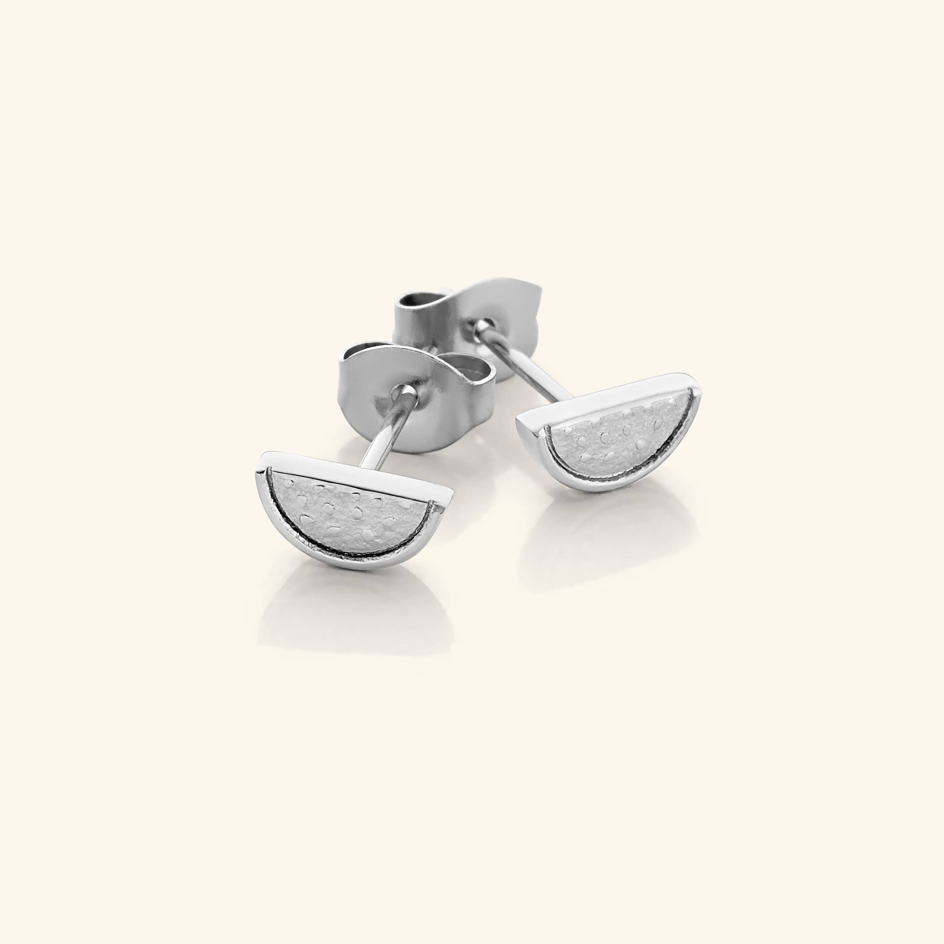 The Watermelon Studs in a polished silver finish, showcasing the semi-circular watermelon slice design with red enamel, black seeds, and green rind detailing, representing the Palestinian flag colors.