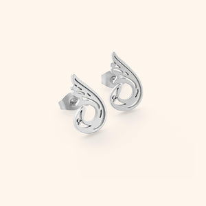 A pair of silver "Serenity Earrings" from the Aadil x Nominal collection. The earrings feature a unique, abstract, teardrop-like design with swirling cut-out details. The image is a product shot, likely showcasing the design and craftsmanship of the earrings.