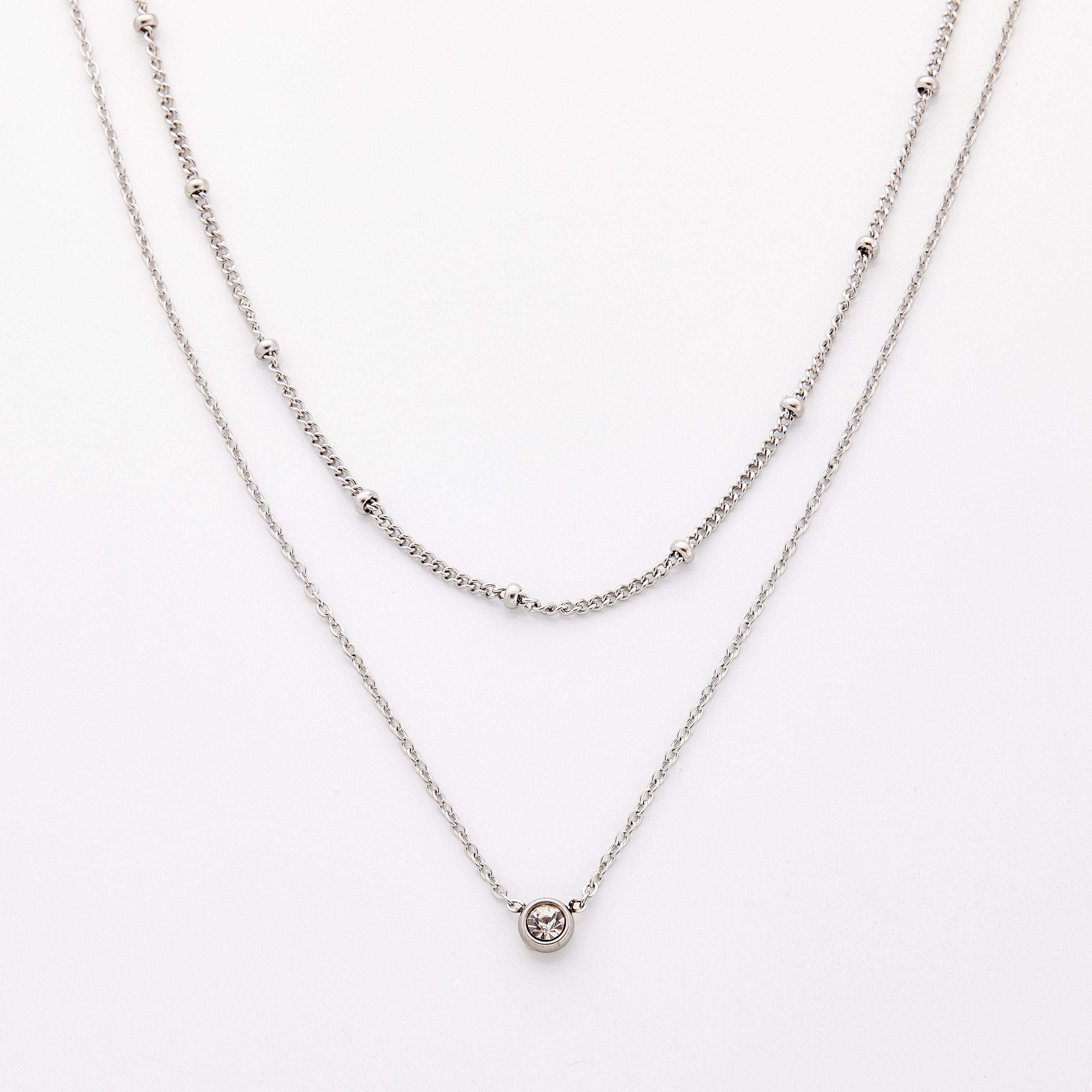 Silver necklace set featuring a bead-accented chain layered with a solitaire bezel-set pendant necklace.